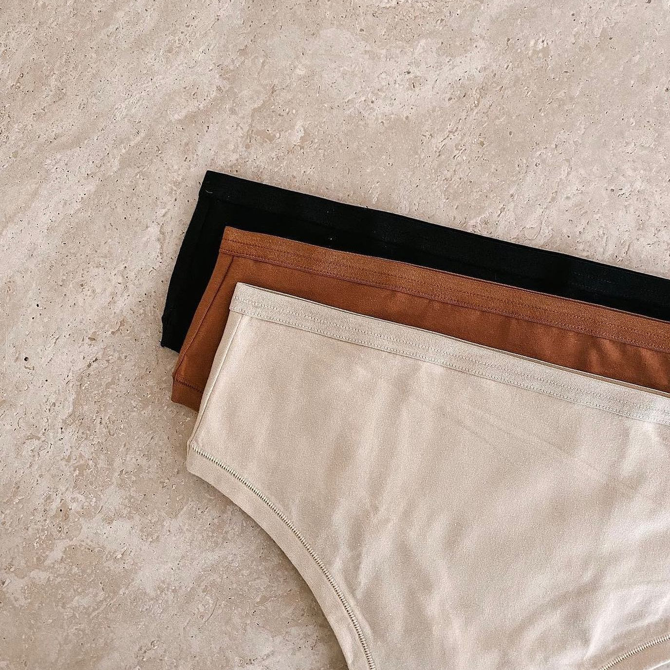  Knickey white, brown, and black panties laying flat on a white background.