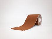 Coffee colored boob tape for brown skin women in a full roll on a white background.